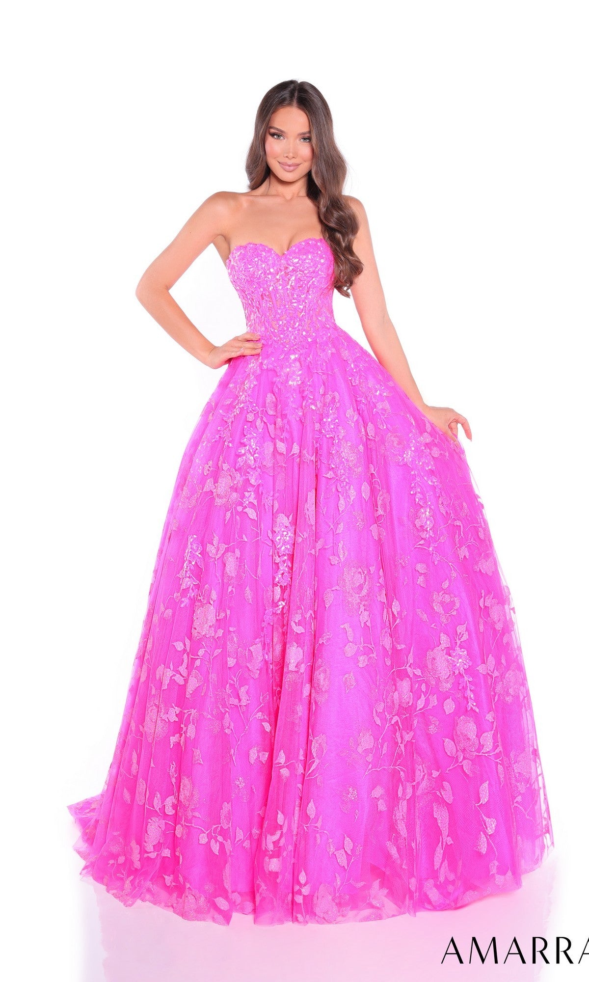 A woman poses against a white background in the Amarra 89513 long prom dress, a strapless bright pink gown featuring floral-embroidered tulle.